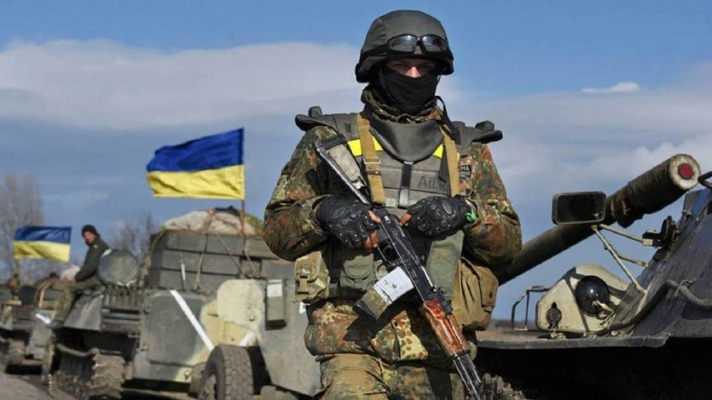 a soldier in front of a tank with the Ukrainian flag