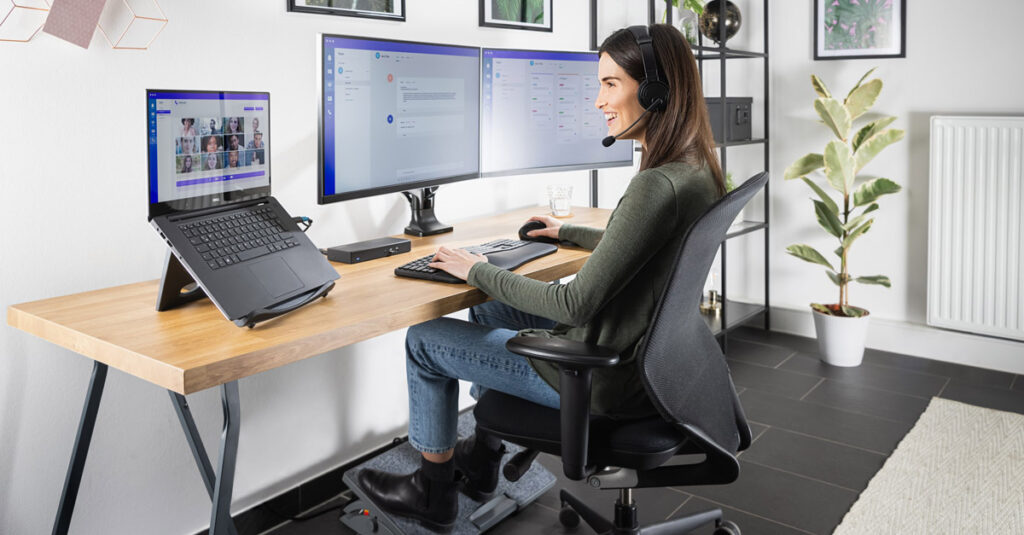 woman standing on ergonomic chair and working on monitors