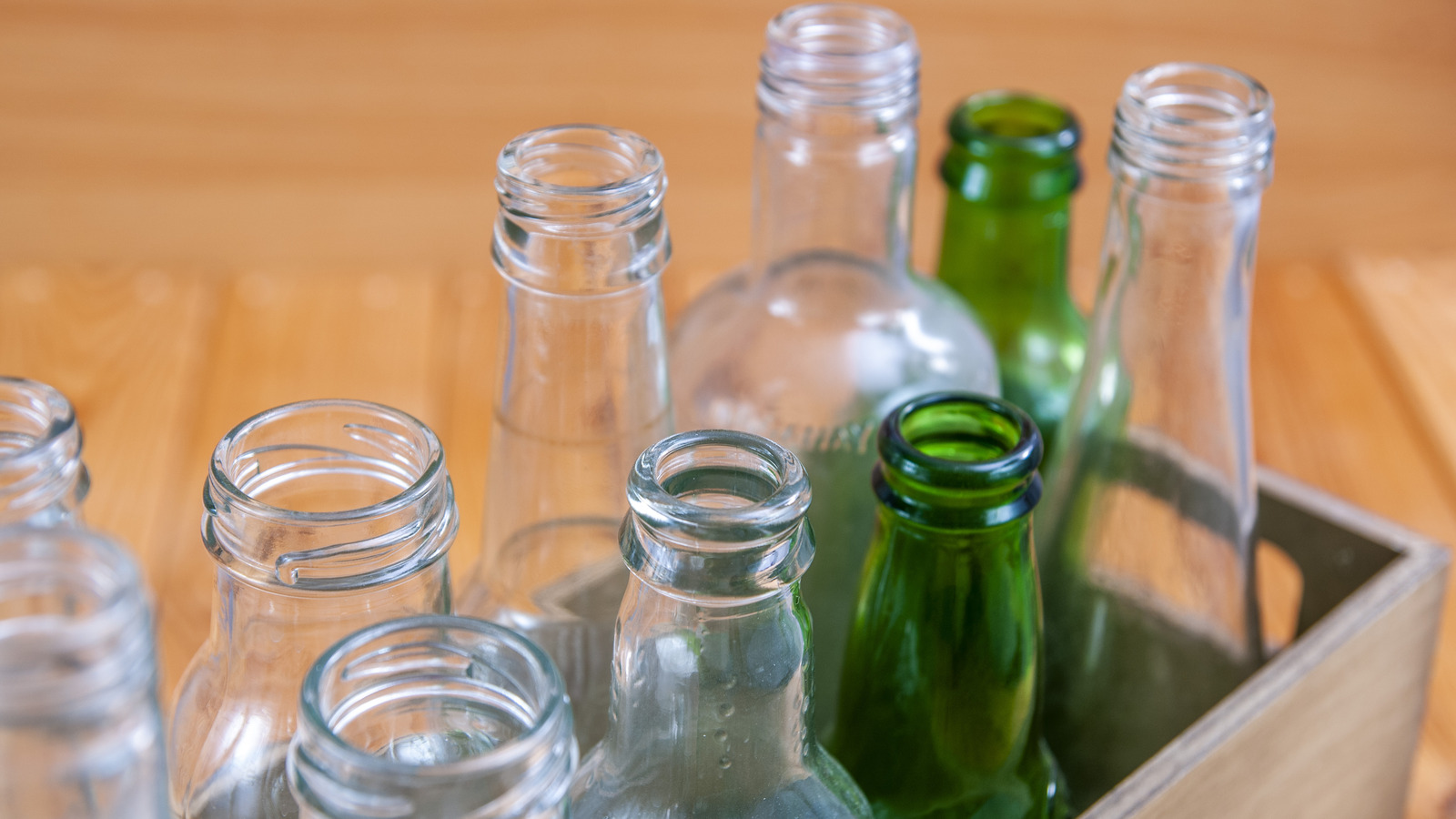 Empty glass bottles in a case on wooden board for recycling